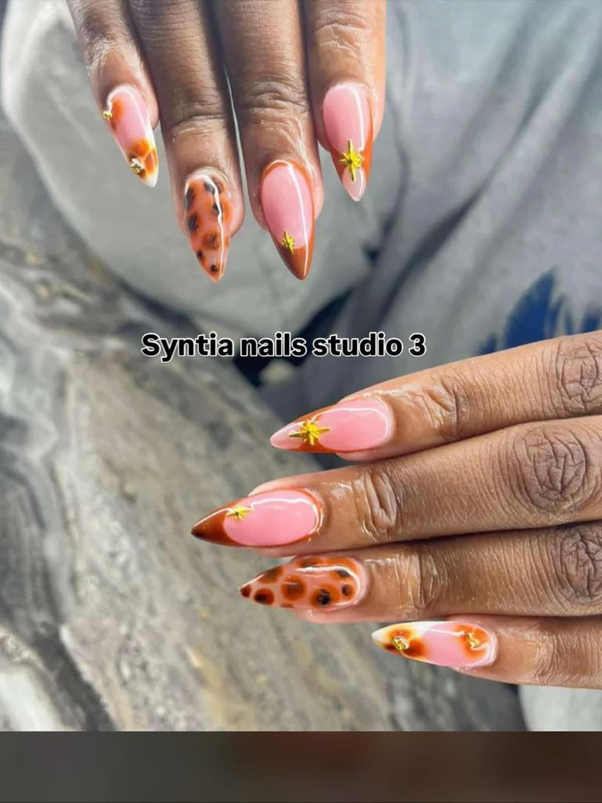 Almond nails in pink with brown tortoiseshell print and gold star charms
