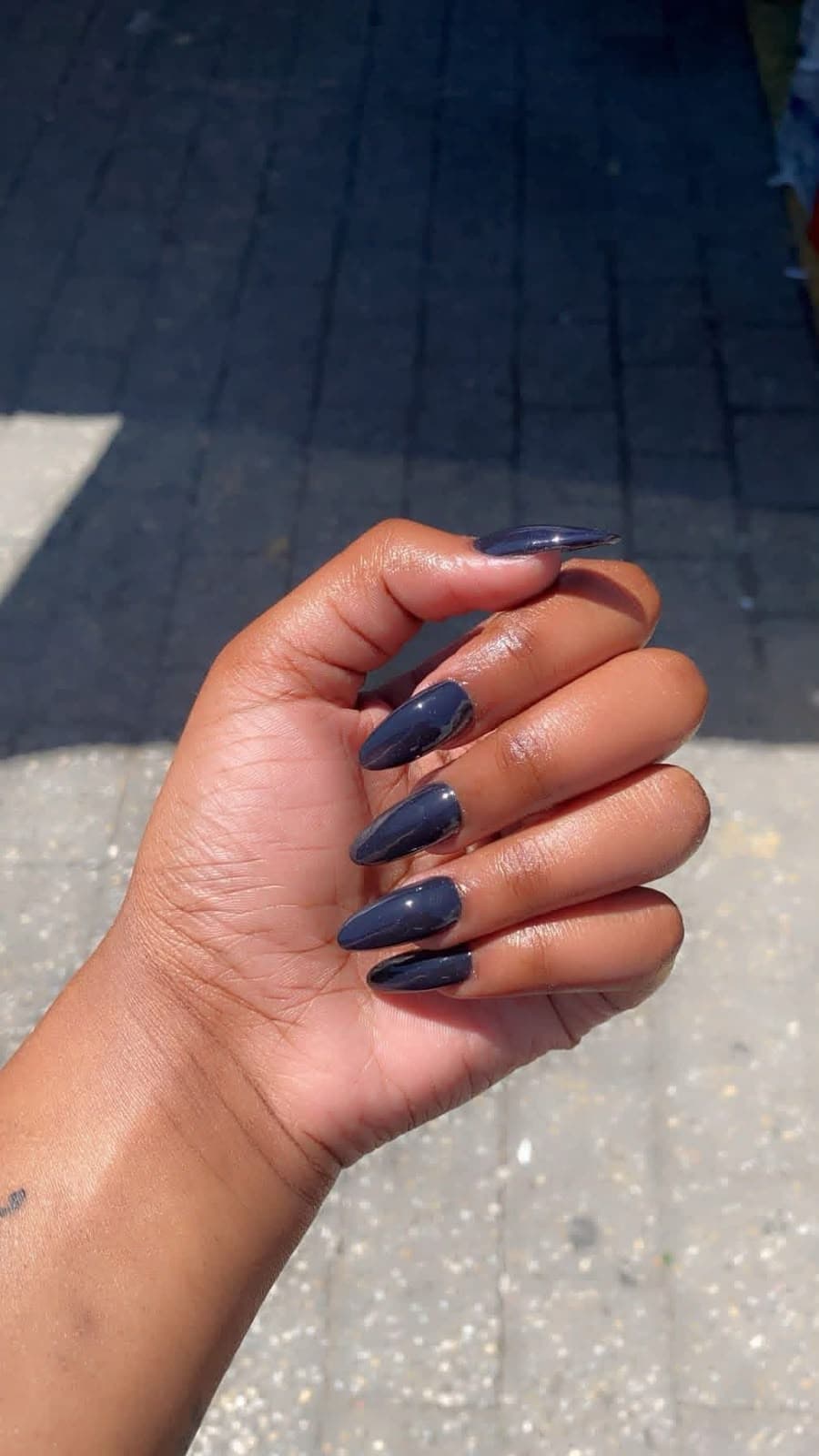 Long almond gel nails in a glossy charcoal navy colour
