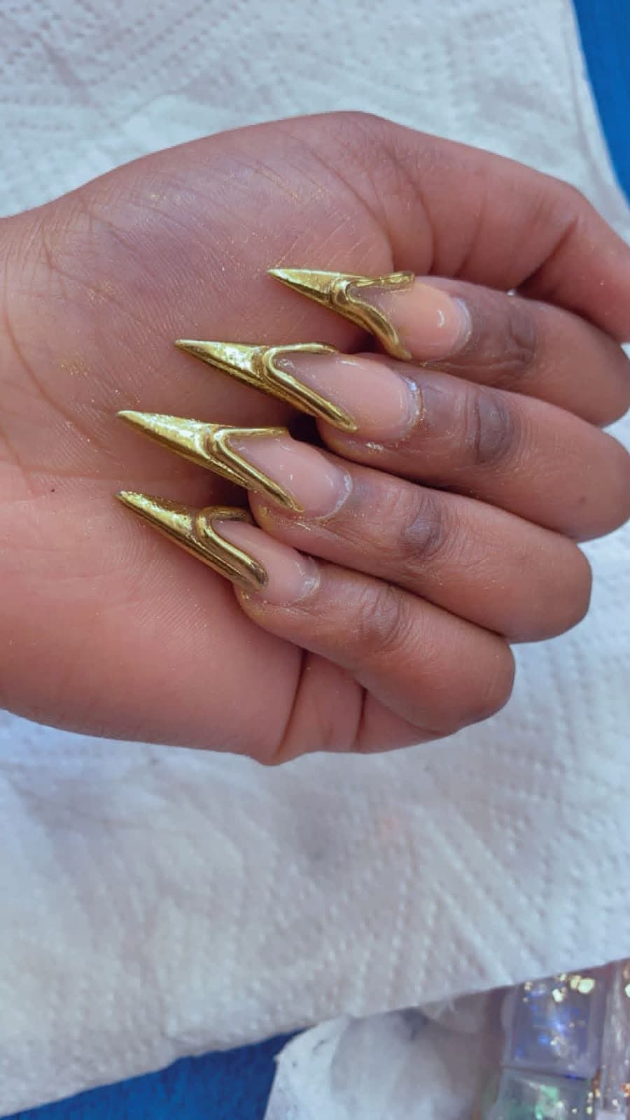 Stiletto nails with sculpted 3D gold chrome tips on a clear nude base